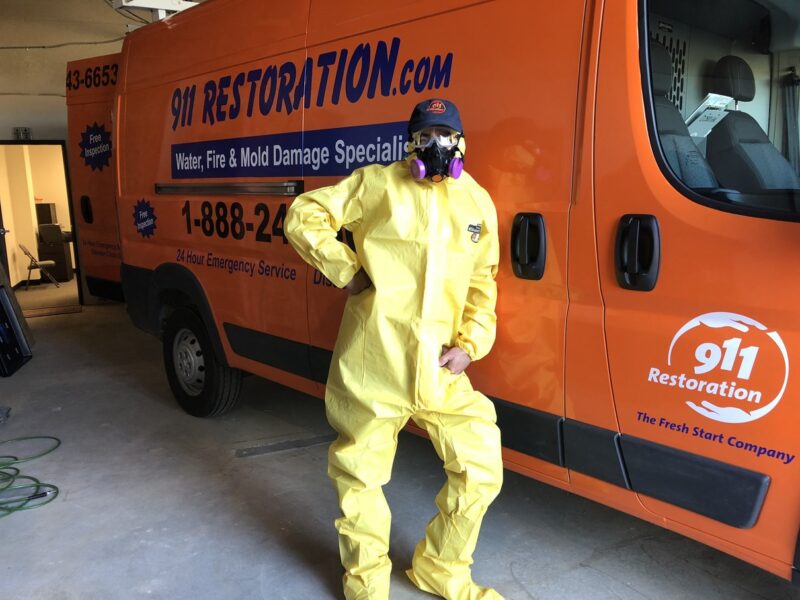 911 Restoration tech wearing a Hazmat suit standing by work van